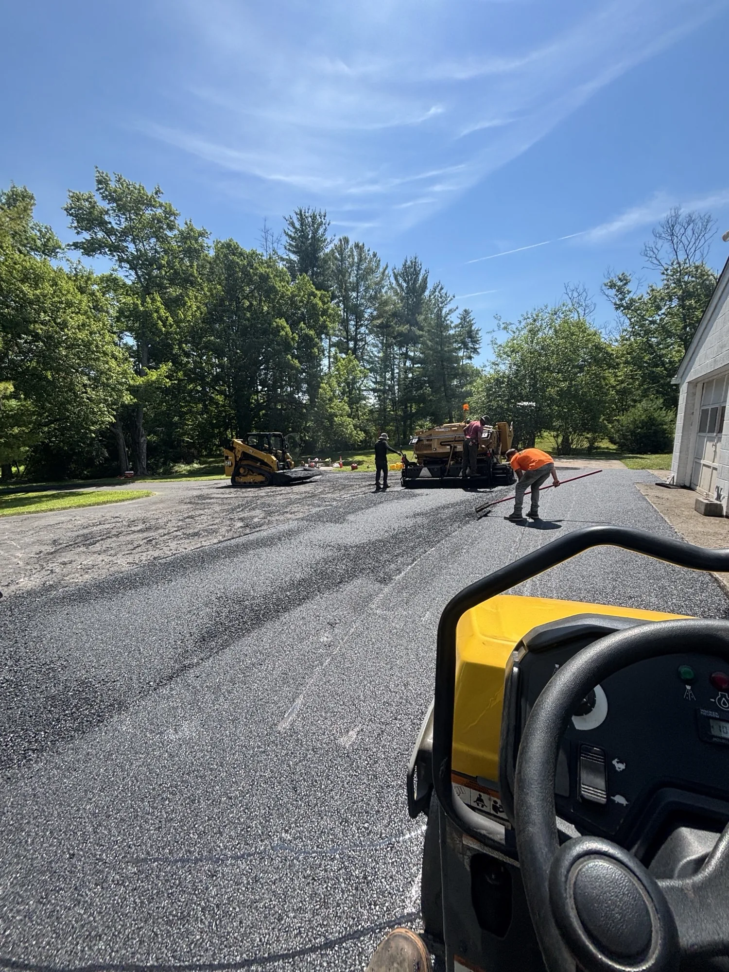 Multiple All County paving trucks and equipment on a wide residential install