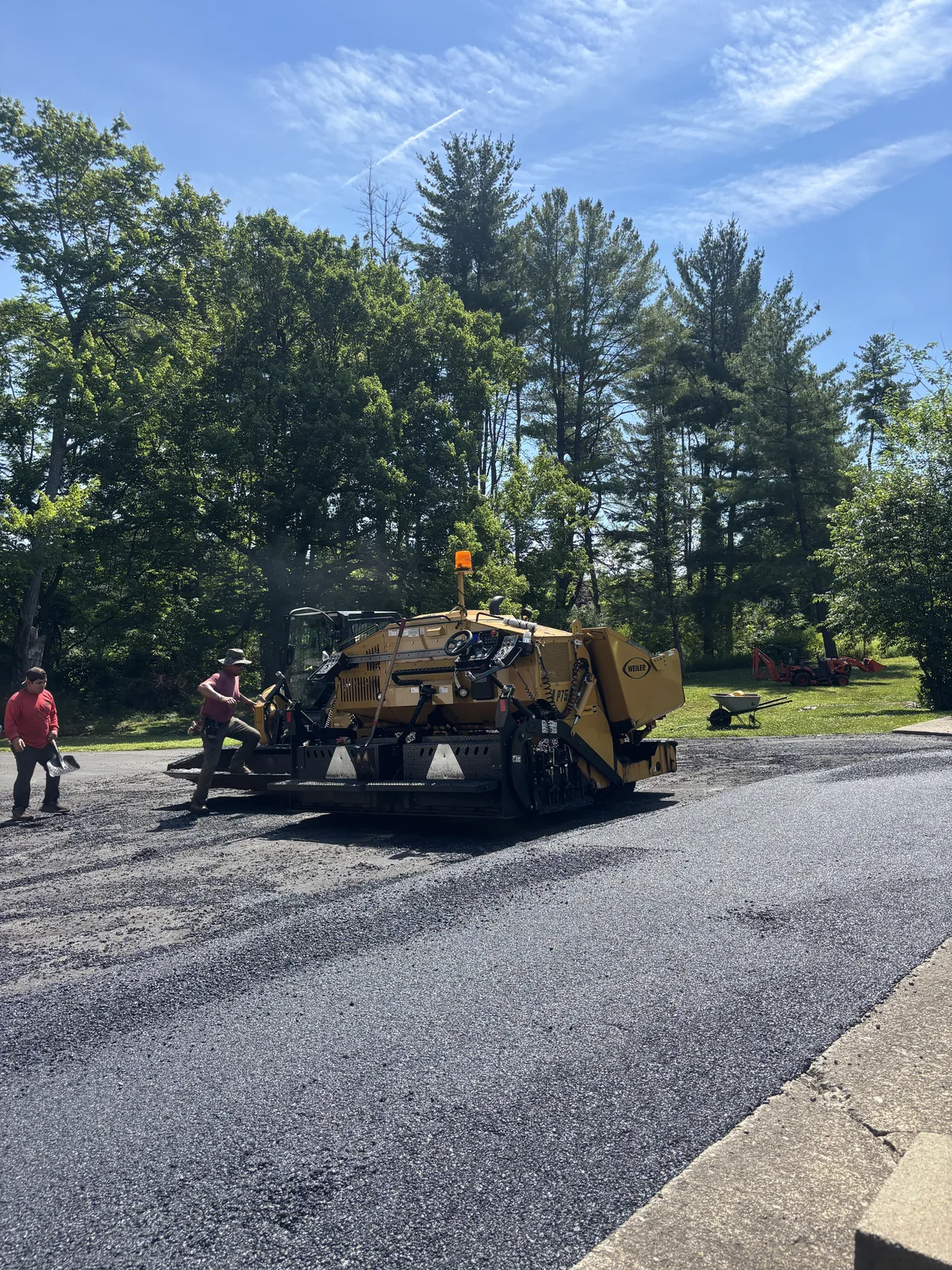 Asphalt paver laying hot-mix asphalt on a residential driveway